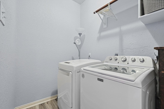 laundry area with a textured wall, laundry area, separate washer and dryer, and wood finished floors