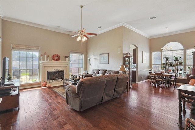 living room with dark wood-style flooring, visible vents, crown molding, and a tiled fireplace