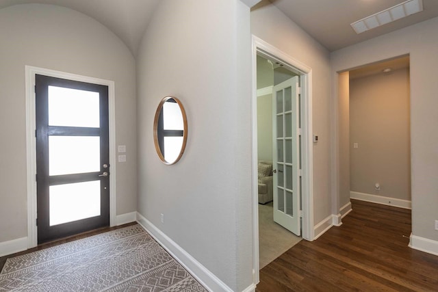 foyer entrance with lofted ceiling, wood finished floors, visible vents, and baseboards