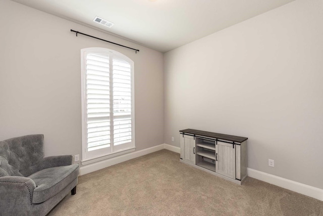 living area with light colored carpet, baseboards, and visible vents