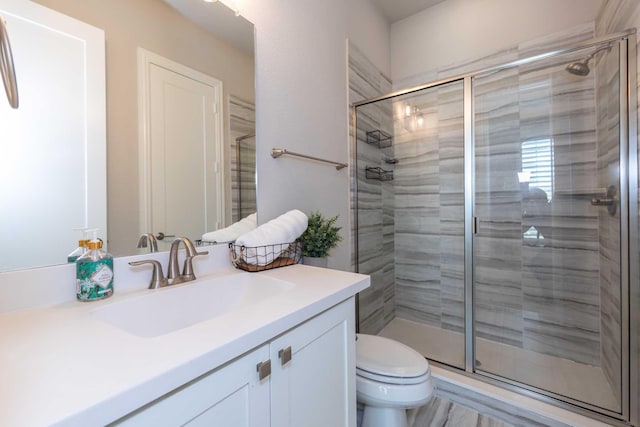 bathroom with a shower stall, toilet, and vanity