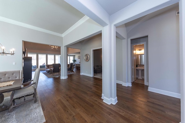 living room with an inviting chandelier, dark wood finished floors, crown molding, and baseboards