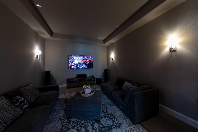 cinema featuring a tray ceiling, visible vents, and baseboards