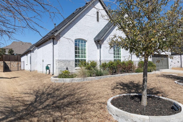 view of side of property with brick siding and fence