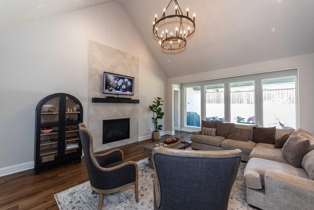 living area with a chandelier, a fireplace, baseboards, and wood finished floors