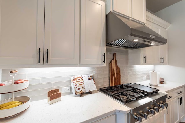 kitchen with light stone counters, stainless steel gas cooktop, white cabinetry, decorative backsplash, and under cabinet range hood