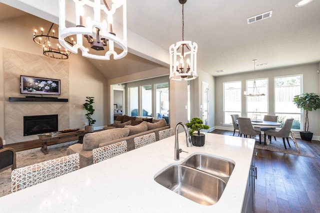 kitchen with a chandelier, a large fireplace, a sink, visible vents, and dark wood finished floors