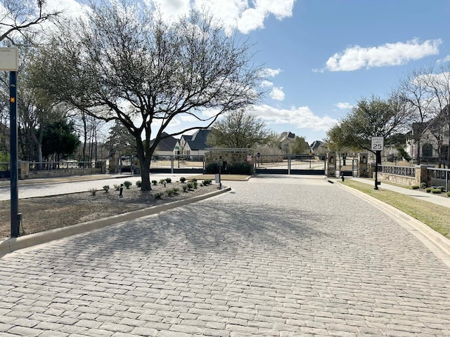 view of road with curbs, traffic signs, sidewalks, and a gate