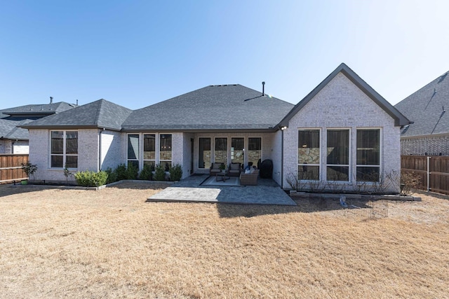 rear view of property with a lawn, a patio, roof with shingles, fence, and brick siding