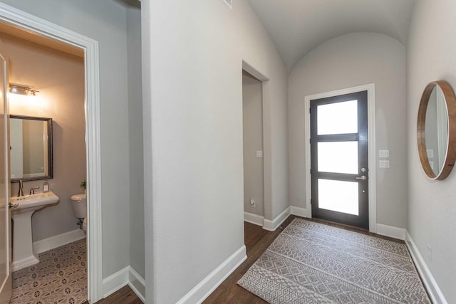 foyer with baseboards, lofted ceiling, and wood finished floors