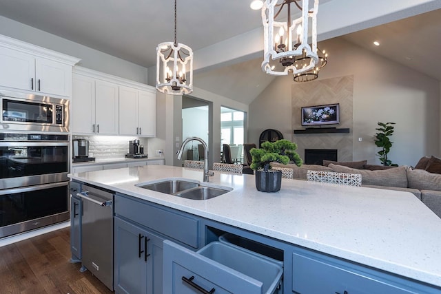 kitchen with a tile fireplace, open floor plan, a notable chandelier, and a sink