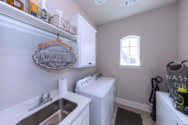 washroom with cabinet space, a sink, baseboards, visible vents, and washing machine and dryer