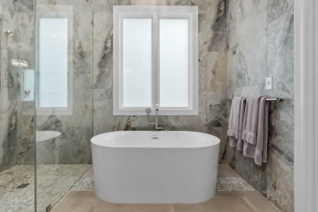 bathroom featuring a freestanding tub, walk in shower, and tile walls