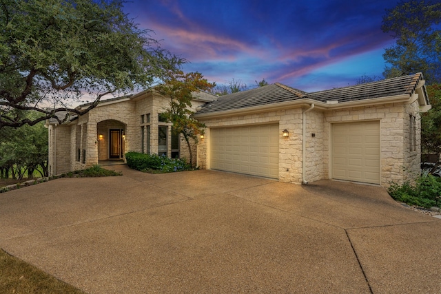 view of front facade featuring a garage, concrete driveway, and a tile roof