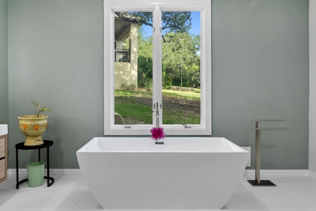 full bath featuring a soaking tub and baseboards