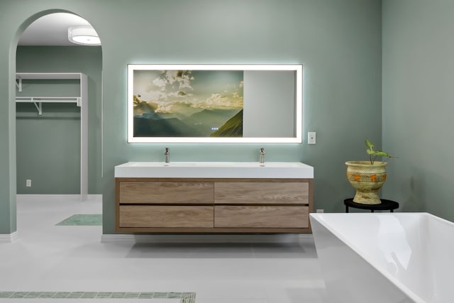 full bath with double vanity, a spacious closet, and a freestanding bath