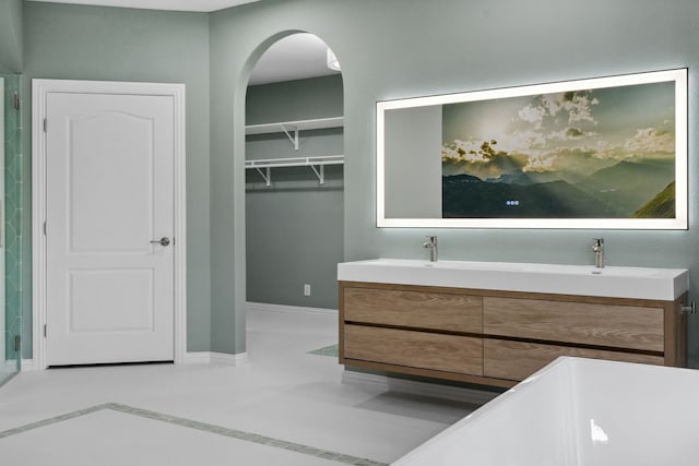 bathroom featuring double vanity, a sink, and baseboards