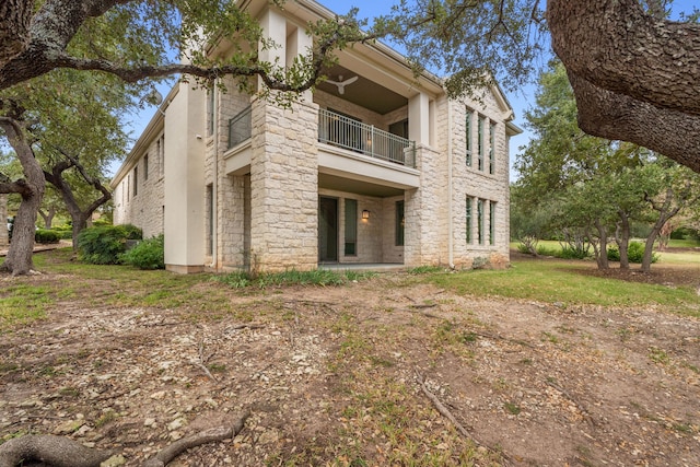 rear view of house with stone siding and a balcony