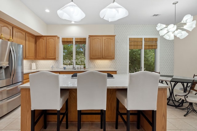 kitchen featuring a breakfast bar, a center island, stainless steel refrigerator with ice dispenser, and wallpapered walls