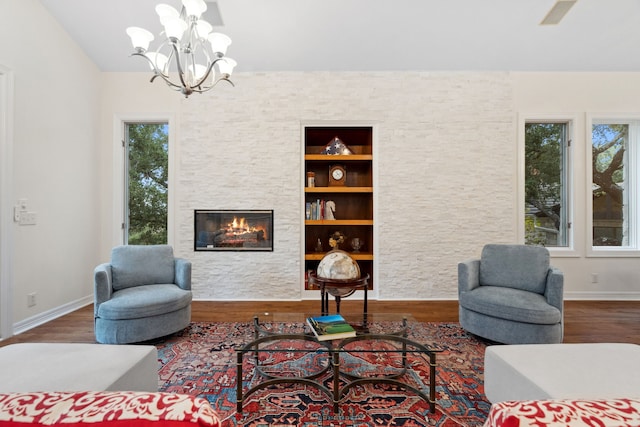 living room with a wealth of natural light, baseboards, wood finished floors, and a stone fireplace