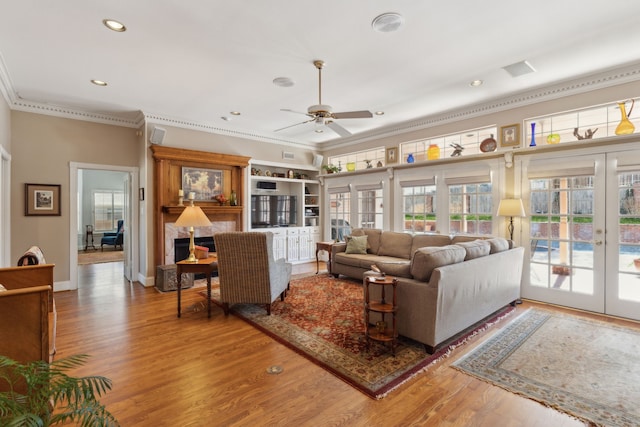 living room featuring baseboards, wood finished floors, crown molding, french doors, and recessed lighting