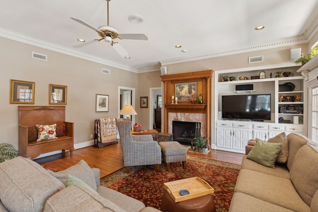 living area featuring a premium fireplace, wood finished floors, and visible vents