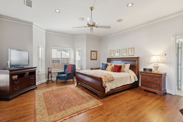 bedroom with recessed lighting, wood finished floors, visible vents, baseboards, and crown molding