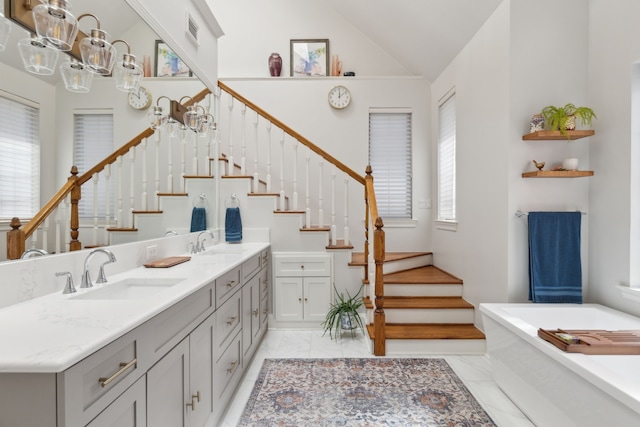 full bathroom with marble finish floor, a soaking tub, visible vents, a sink, and plenty of natural light