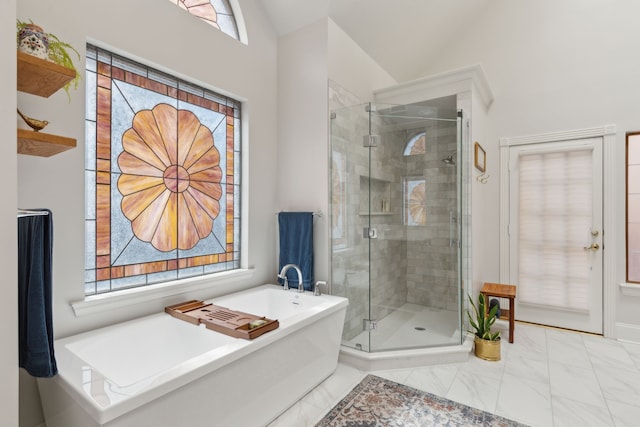 bathroom featuring vaulted ceiling, a stall shower, a freestanding tub, and a wealth of natural light