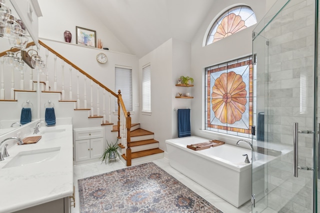 bathroom featuring a stall shower, marble finish floor, a sink, and double vanity