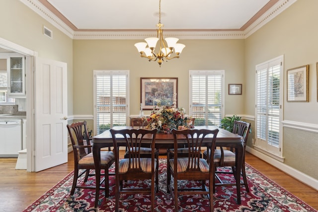 dining space featuring visible vents, plenty of natural light, a notable chandelier, and wood finished floors