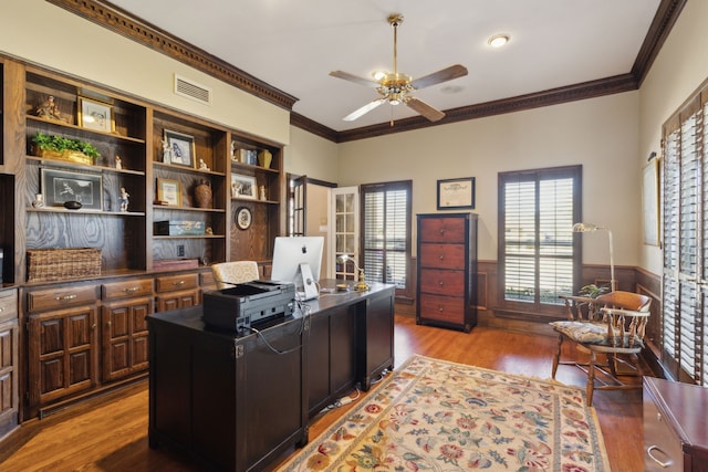 office featuring visible vents, ornamental molding, wainscoting, ceiling fan, and wood finished floors