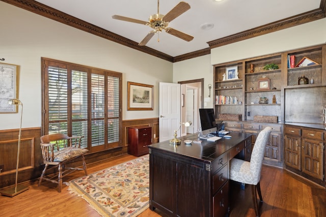 office space with wainscoting, wood finished floors, a ceiling fan, and crown molding