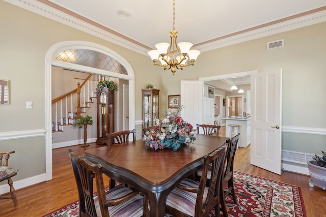 dining space featuring crown molding, visible vents, wood finished floors, baseboards, and stairs