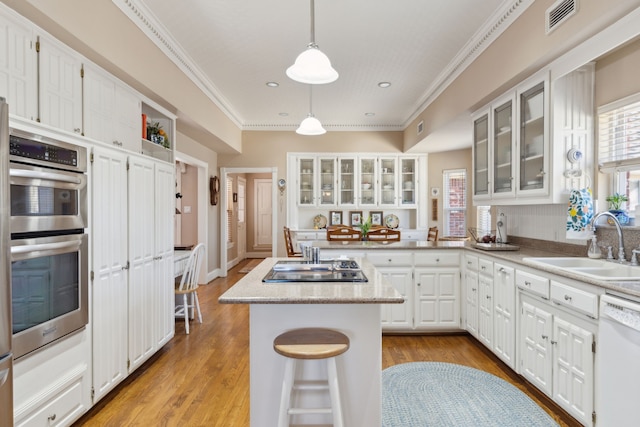 kitchen featuring double oven, a sink, visible vents, ornamental molding, and dishwasher