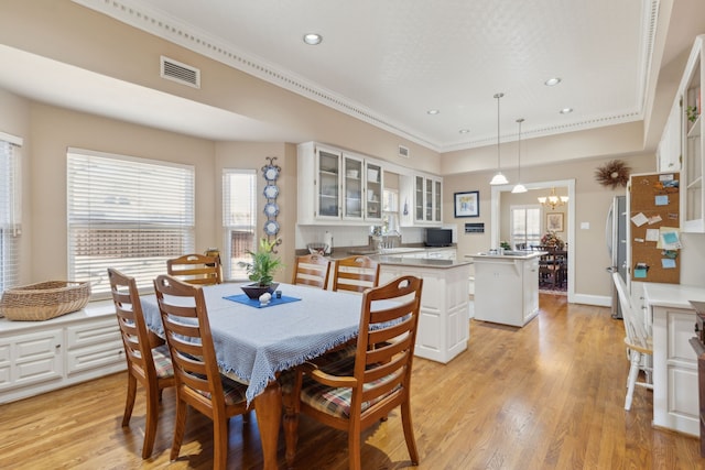 dining area with a wealth of natural light, light wood-type flooring, a chandelier, and visible vents