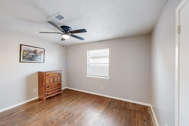 empty room with ceiling fan, visible vents, baseboards, and wood finished floors