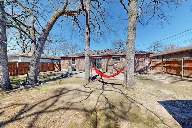 rear view of house with cooling unit, a patio, brick siding, and a fenced backyard