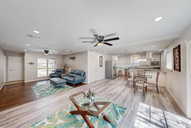 living room featuring recessed lighting, visible vents, light wood finished floors, and baseboards