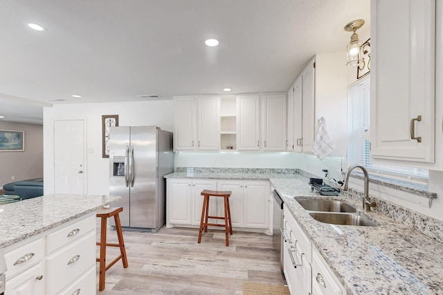 kitchen featuring visible vents, a sink, open shelves, stainless steel appliances, and light wood finished floors