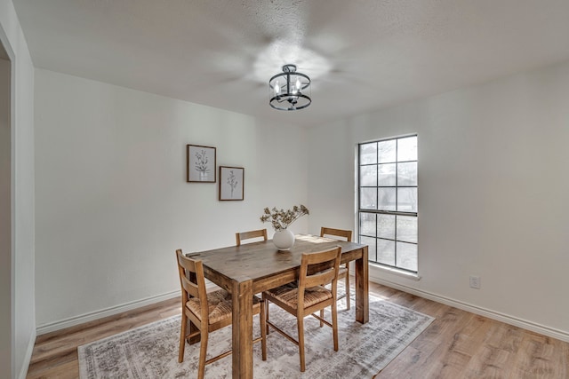 dining room featuring light wood-type flooring, baseboards, and an inviting chandelier