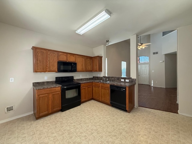 kitchen with black appliances, brown cabinetry, dark countertops, and visible vents