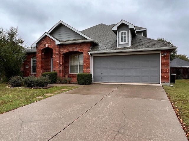 traditional home featuring a shingled roof, concrete driveway, an attached garage, a front lawn, and brick siding