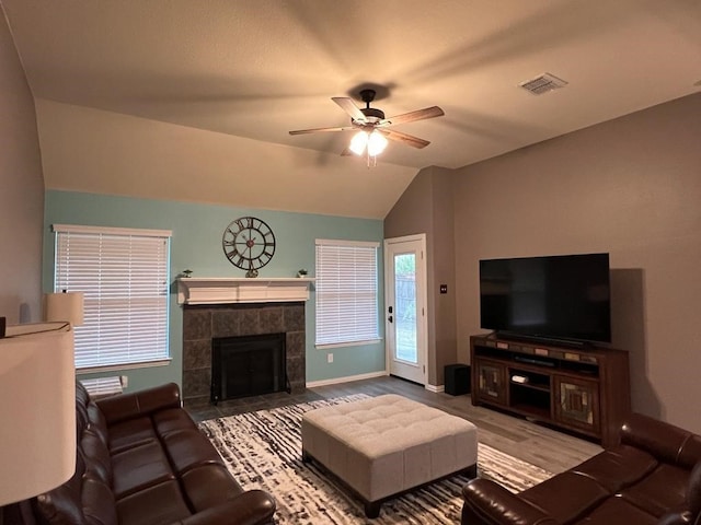 living room with visible vents, baseboards, ceiling fan, vaulted ceiling, and a fireplace