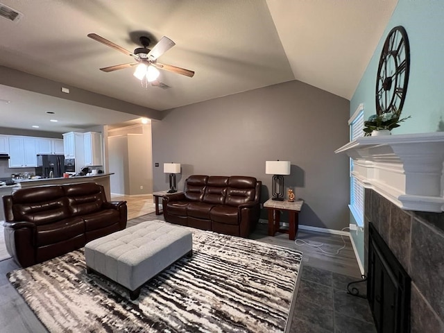 living room with baseboards, visible vents, a tiled fireplace, lofted ceiling, and ceiling fan