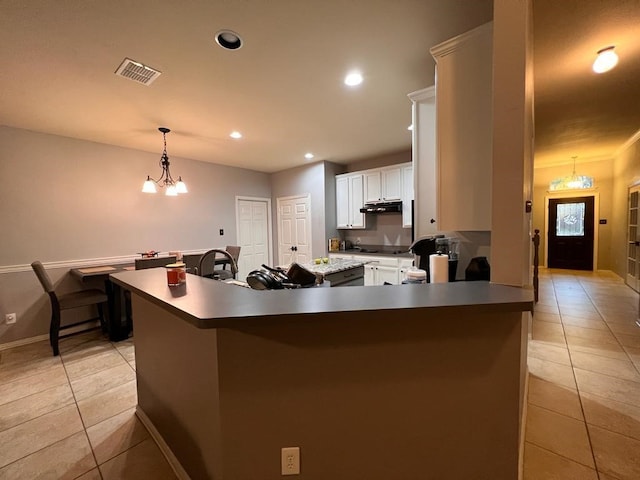 kitchen with under cabinet range hood, light tile patterned floors, visible vents, and an inviting chandelier