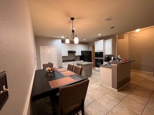 kitchen featuring visible vents, a peninsula, black appliances, white cabinetry, and a sink