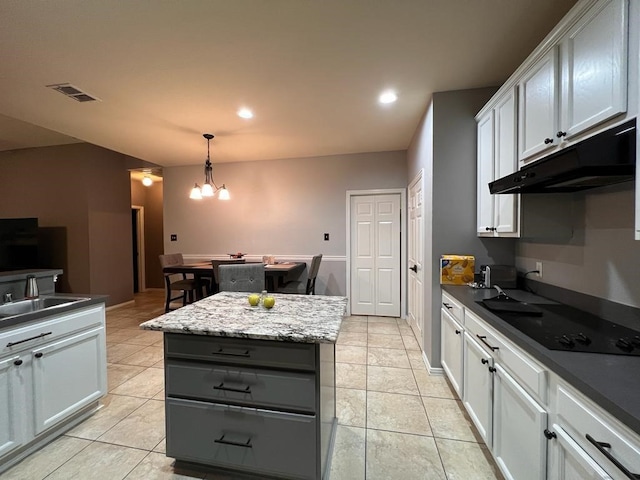 kitchen featuring visible vents, a kitchen island, black electric stovetop, under cabinet range hood, and a sink