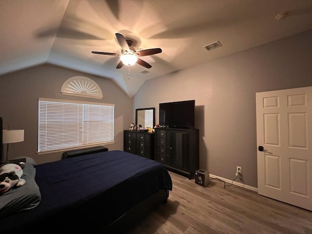 bedroom with ceiling fan, visible vents, vaulted ceiling, and wood finished floors