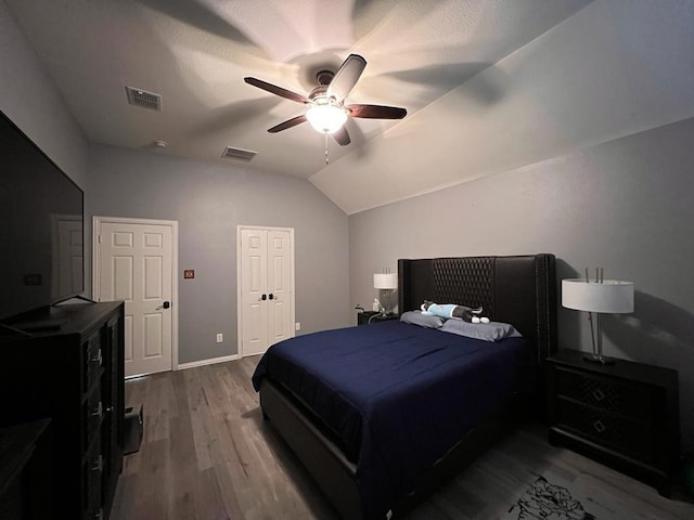 bedroom with lofted ceiling, dark wood-style floors, visible vents, and a ceiling fan